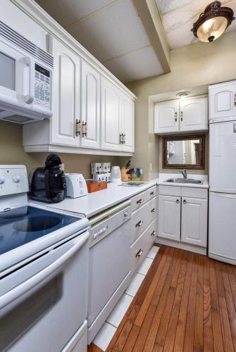 a kitchen with white appliances and a wooden floor at Noble Waterfront Suites in Brockville