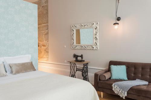 a bedroom with a bed and a chair and a mirror at Ribeira Historic Apartments in Porto