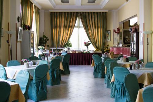 a dining room with tables and chairs with green chairs at Hotel degli Amici in Artena