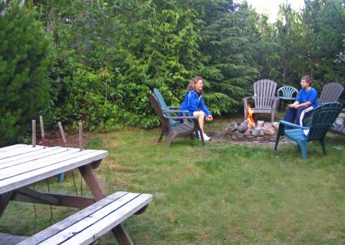 two people sitting in chairs around a camp fire at Summerhill Guest House in Tofino