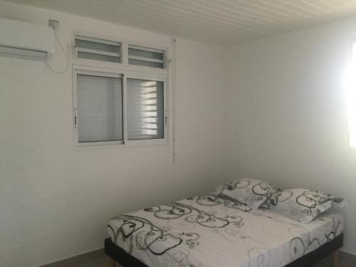 a bedroom with a bed and a window at Villa Fleur de Canne in Saint-Louis