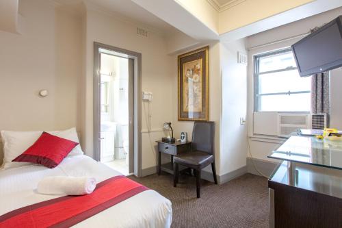 a bedroom with a bed and a desk and a television at City Square Motel in Melbourne