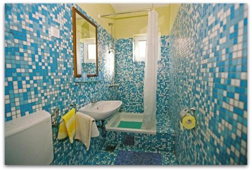 Baño de azulejos azules con lavabo y espejo en Bubi Hvar Apartments 1, en Hvar