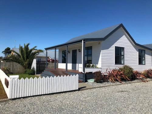 a white house with a fence in front of it at Amberlea Cottages in Hokitika