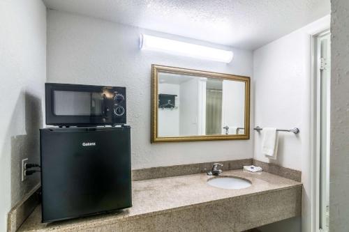 a bathroom with a sink and a tv and a mirror at Trade Wind Motel in Jacksonville