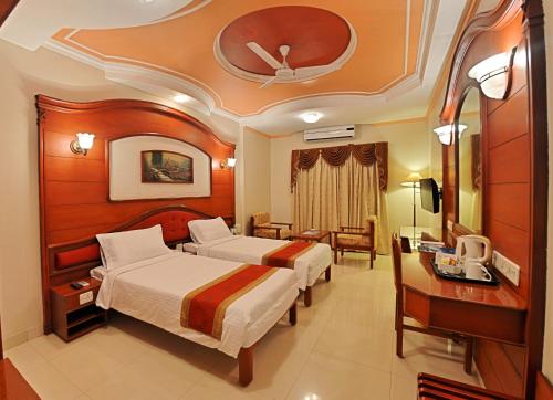Habitación de hotel con 2 camas y escritorio en Hotel Gnanam, en Thanjāvūr