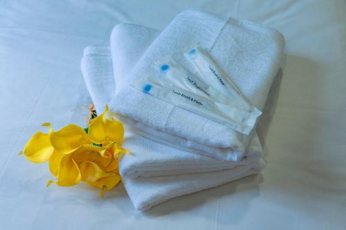 a pile of towels and a flower on a table at LightHouse Hotel & ShortStay @ Damansara Uptown in Petaling Jaya