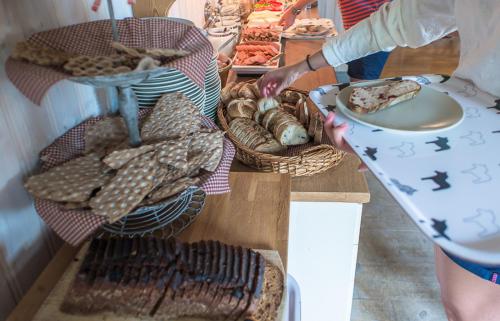 a person reaching for food on a table with baskets of food at Backlund Boende i Dalarna in Rättvik