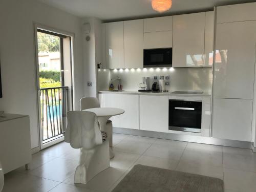サントロペにあるExclusive Resort Apartment Saint Tropezの白いキャビネット、テーブルと椅子付きのキッチンが備わります。