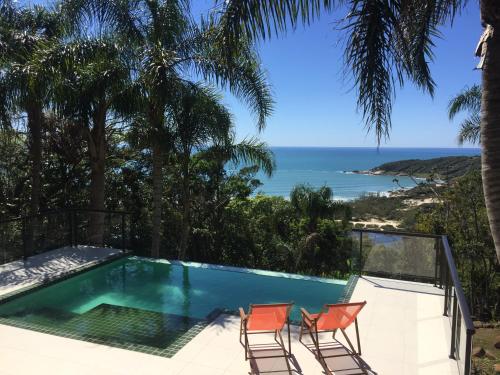 a pool with chairs and a view of the ocean at Pousada The Rosebud in Praia do Rosa