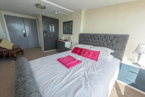 a bedroom with a large bed with pink pillows on it at Villa Mentone Hotel in Shanklin