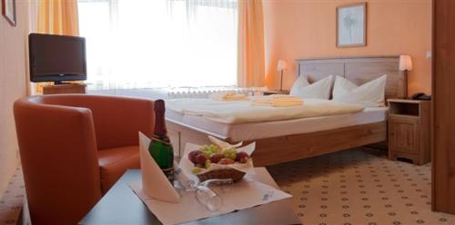 a hotel room with a bed and a desk with a chair at Landhotel Harz in Thale
