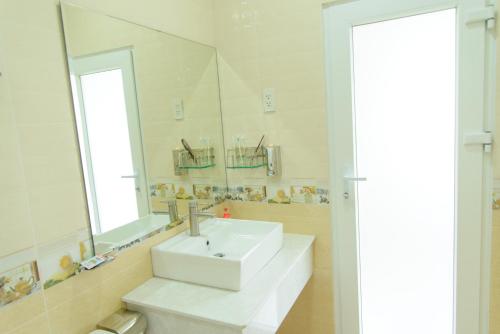 Hung Long Hotel في Ben Tre: حمام مع حوض أبيض ومرآة