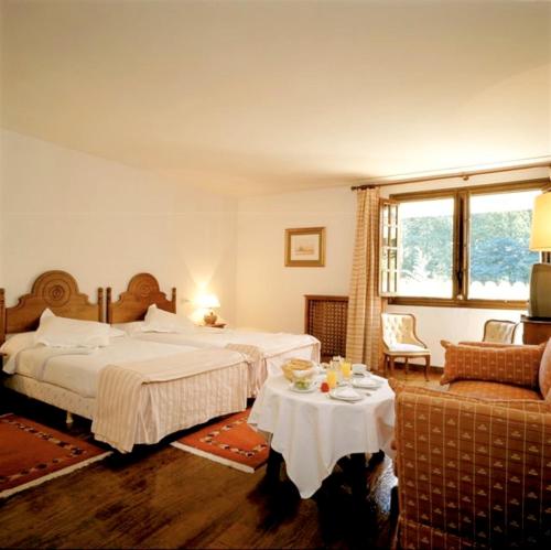a hotel room with two beds and a table at Parador de Santillana del Mar in Santillana del Mar