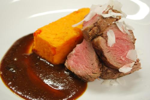 a piece of meat with sauce on a white plate at Černá louže in Branžež