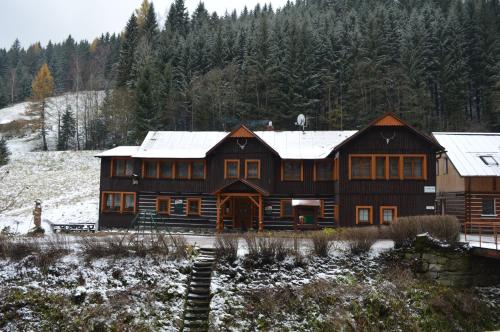 a large wooden house with snow on the roof at Pension Čertice in Pec pod Sněžkou