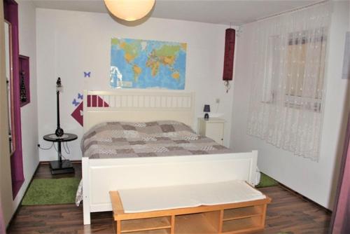 Un dormitorio con una cama blanca y un mapa en la pared en Ferienwohnung Im Liestengarten, en Auggen