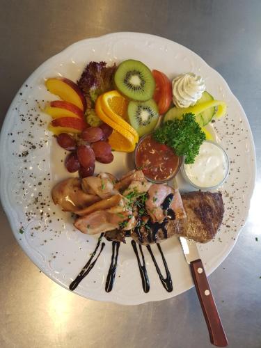 a plate of food with meat and fruits and vegetables at Gästehaus Bärwald in Seeboden