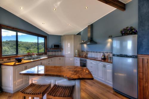 a kitchen with a wooden table and a refrigerator at Mayakitana ~ Overlooking the golf course in Coles Bay