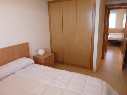 ペニスコラにあるApartamentos Deluxe Pompeya 1の白いベッドと木製キャビネット付きのベッドルーム1室が備わります。