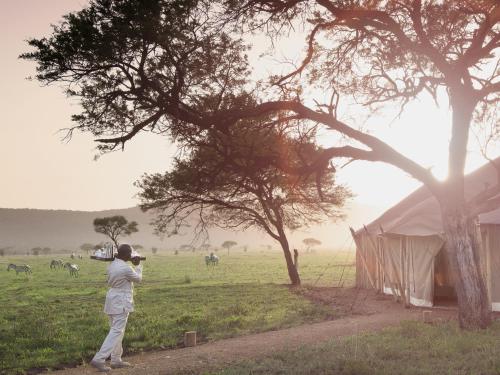 a man taking a picture of a field with a tent at One Nature Nyaruswiga Serengeti in Banagi