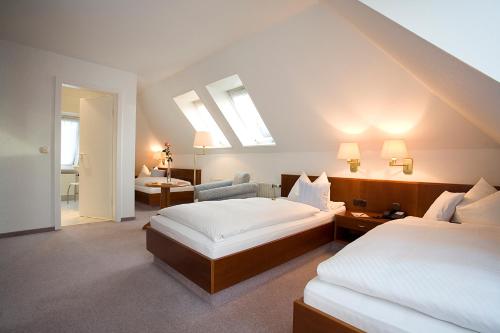a hotel room with two beds and a chair at Ringhotel Residenz Wittmund in Wittmund