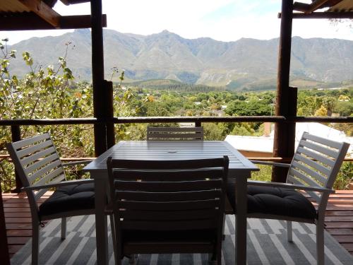 a table and chairs on a porch with a view of mountains at Mountain View Swellendam in Swellendam