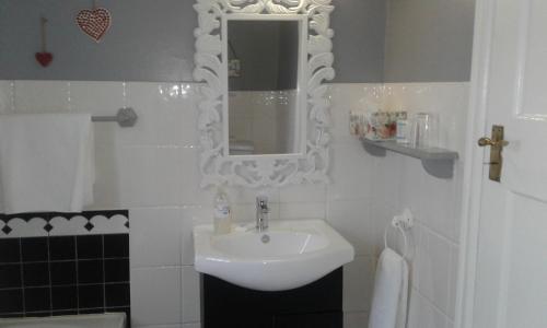 a white bathroom with a sink and a mirror at Eastbury Cottage in Hermanus