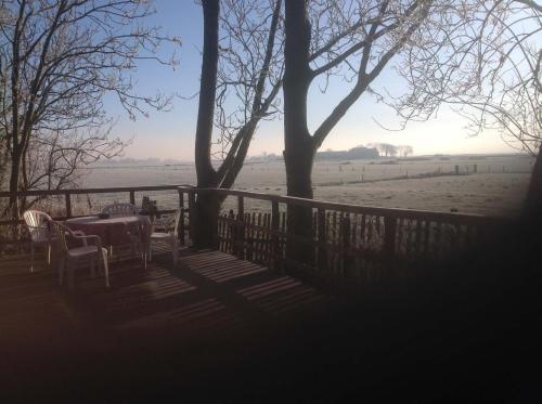 a table and chairs on a porch with a view of a field at Chalet westerham in Winsum