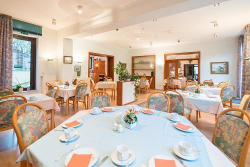 un comedor con mesas y sillas blancas en Hotel-Barbarossa-Garni bei Hanau en Rodenbach