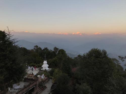 a view of a hill with a temple and trees at The Fort Resort in Nagarkot