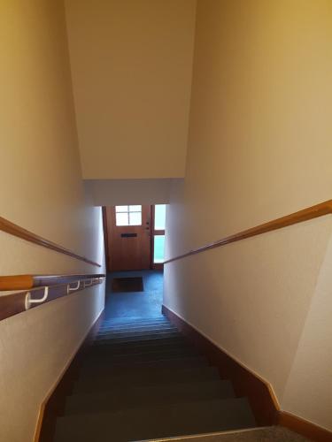 a hallway with stairs leading up to a door at No 52 - Apartment with Lounge and Dining Area - No kitchen in Ullapool