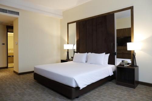 Louis Tavern Hotel في بانكوك: غرفة فندقية بسرير كبير ومصباحين