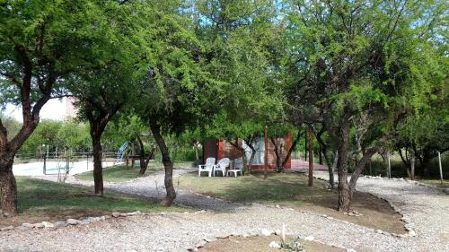 a group of trees with white chairs in a park at Cabañas Quinco in Merlo