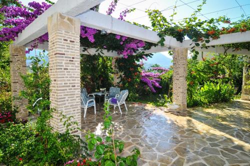 a patio with a table and chairs under a pergola with flowers at Apartments Villa Stankovic in Tivat