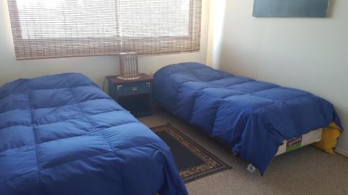 2 camas en una habitación con sábanas azules en Edificio Maritim Algarrobo, en Algarrobo