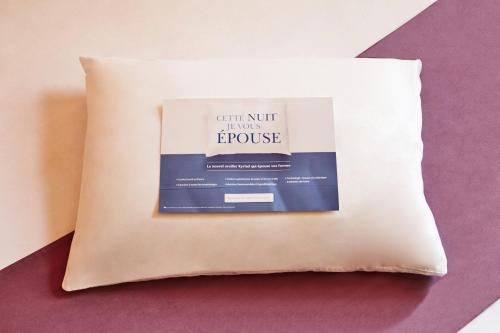 a pillow with a book sitting on top of it at Kyriad Hôtel La Fleche in La Flèche