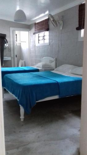 a bedroom with two beds with blue sheets at La grange de G. in Grand Gaube