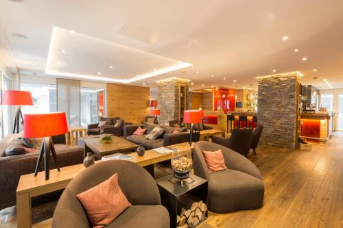 a large living room with couches and chairs at Hotel Crown in Andermatt