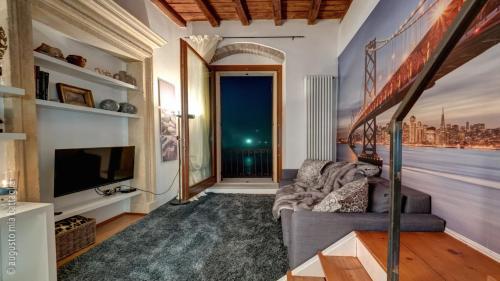 Casa Archi - Balcone sul Fiume في فيرونا: غرفة معيشة بها أريكة وتلفزيون