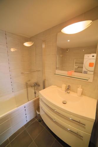 une salle de bain avec un lavabo, une baignoire et un miroir dans l'établissement Beau Rivage Appart', à Souffelweyersheim