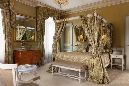 a bedroom with a canopy bed and a table at Hôtel L'Ecrin in Honfleur