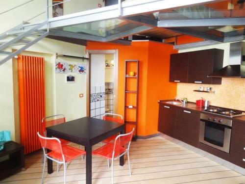 ミラノにあるNolo Loft in Milanの黒いテーブルとオレンジの壁が備わるキッチン