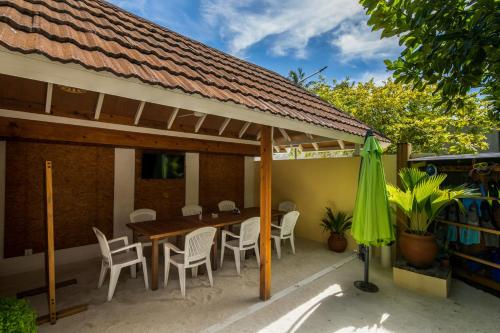 a patio with a table and chairs and a umbrella at Holiday Garden Rasdhoo in Rasdu