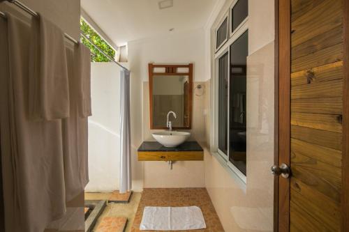een badkamer met een wastafel en een spiegel bij Holiday Garden Rasdhoo in Rasdu