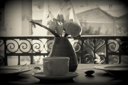 a table with a vase with flowers and a coffee cup at BB La Bella Addormentata e il Principe Calaf in Lucca