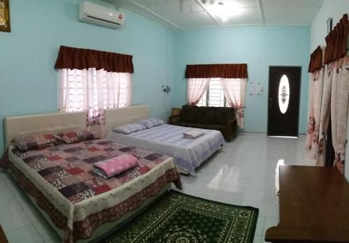 a bedroom with two beds and a couch in it at Dhia Irdina Homestay in Paya Rewak