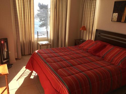 1 dormitorio con cama roja y ventana en Pinares del Canelillo en Algarrobo, en Algarrobo