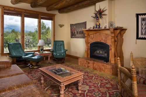 a living room with a fireplace and green chairs at Blue Lake Ranch in Hesperus