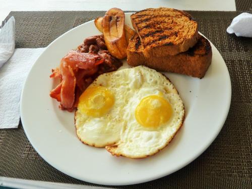 a plate of breakfast food with eggs bacon and toast at Miller's Guest House in Buccoo